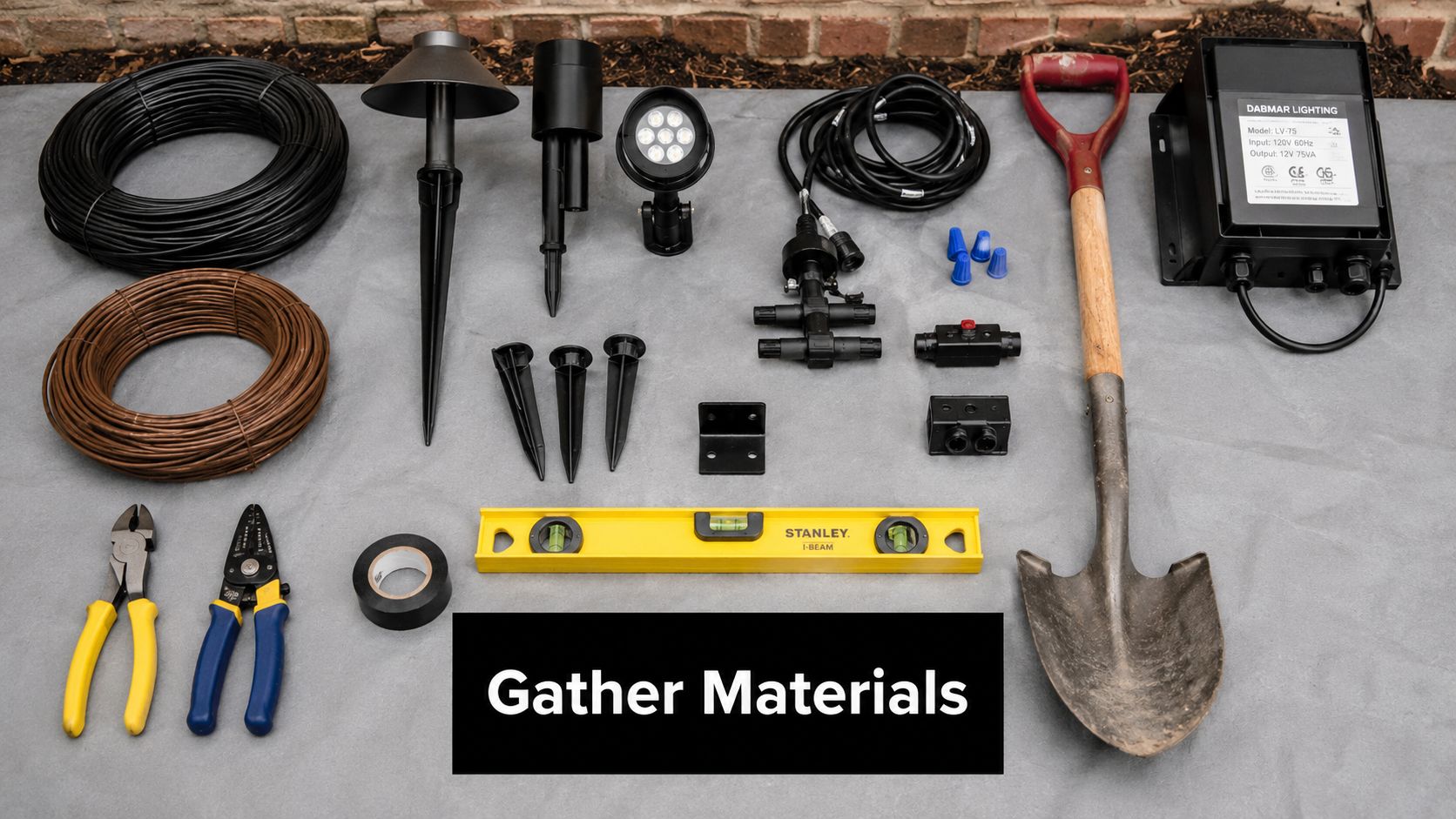 A top-down view of tools and components for an outdoor lighting installation project arranged on a mat.